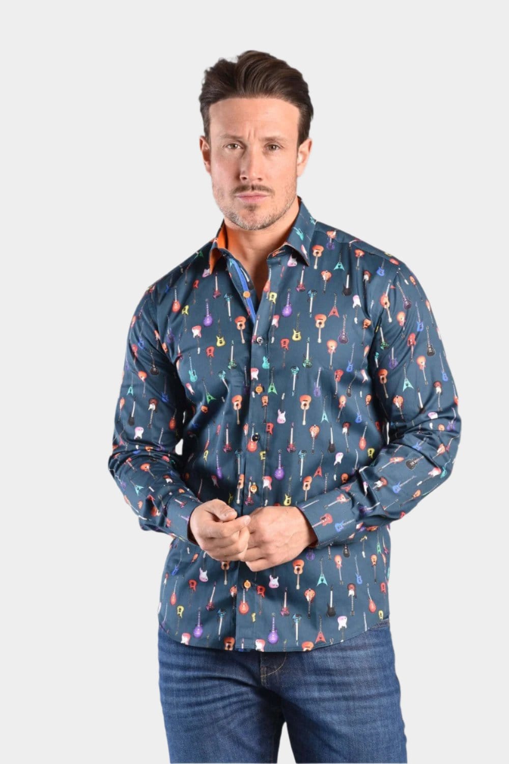 A man wearing a navy Claudio Lugli shirt with a guitars pattern, paired with blue jeans and brown leather shoes.