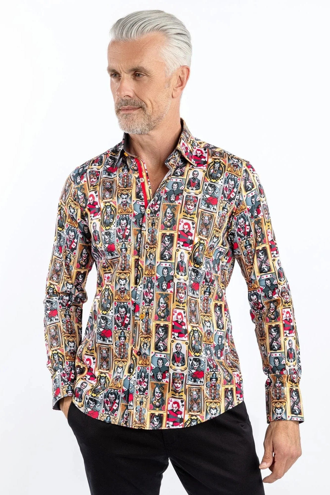 A man wearing a Claudio Lugli long-sleeve shirt with a bold joker-themed print in gold, red, and black, paired with dark trousers.
