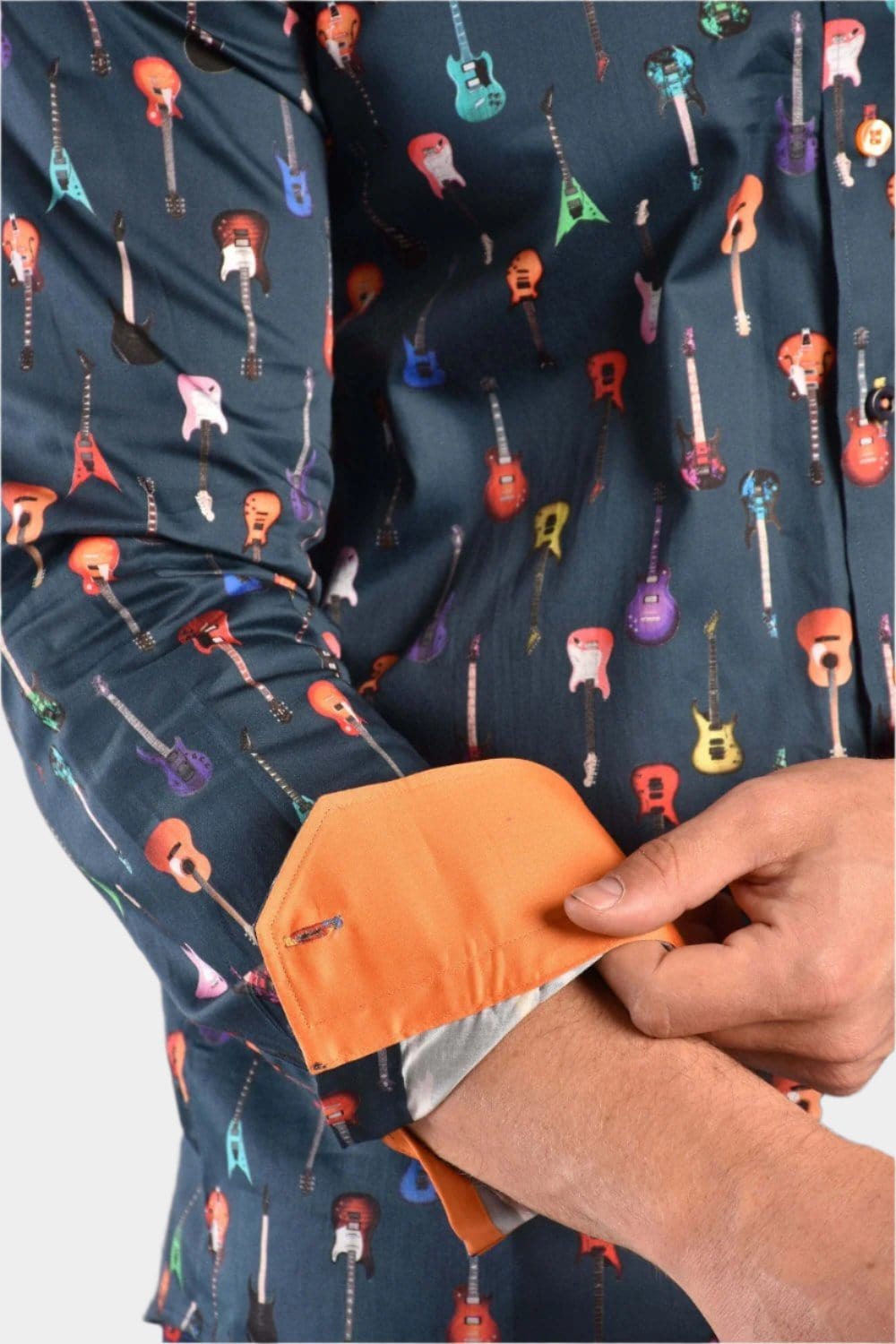 A man wearing a navy Claudio Lugli shirt with a guitars pattern, showing the inside of the sleeve cuff that is orange.