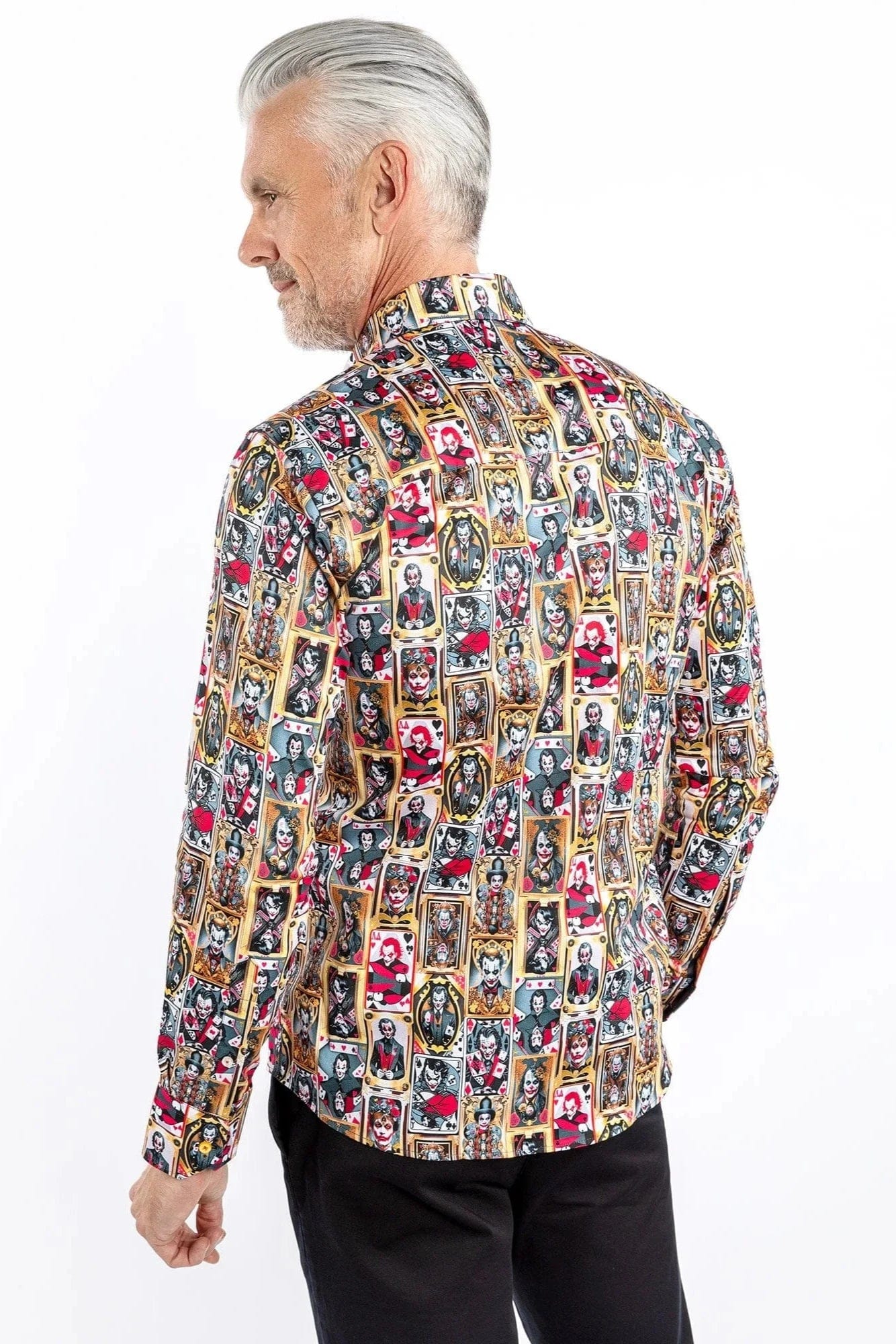 A man wearing a Claudio Lugli long-sleeve shirt with a bold joker-themed print in gold, red, and black, paired with dark trousers.