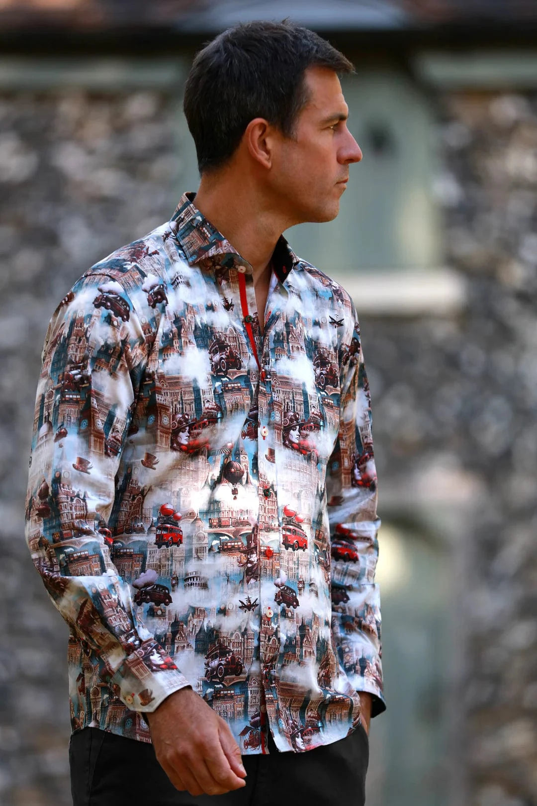 A man wearing a Claudio Lugli steampunk city print shirt with a blend of vintage architecture and mechanical elements, in a satin-cotton fabric.
