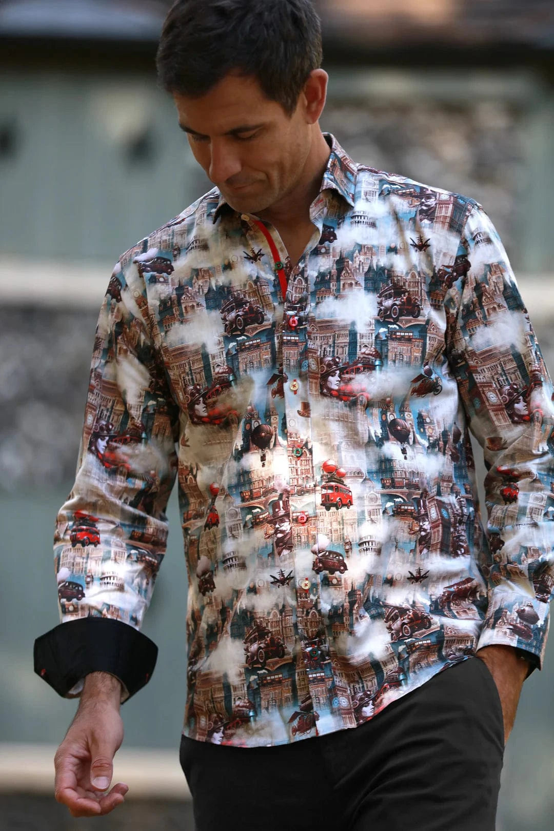 A man wearing a Claudio Lugli steampunk city print shirt with a blend of vintage architecture and mechanical elements, in a satin-cotton fabric.