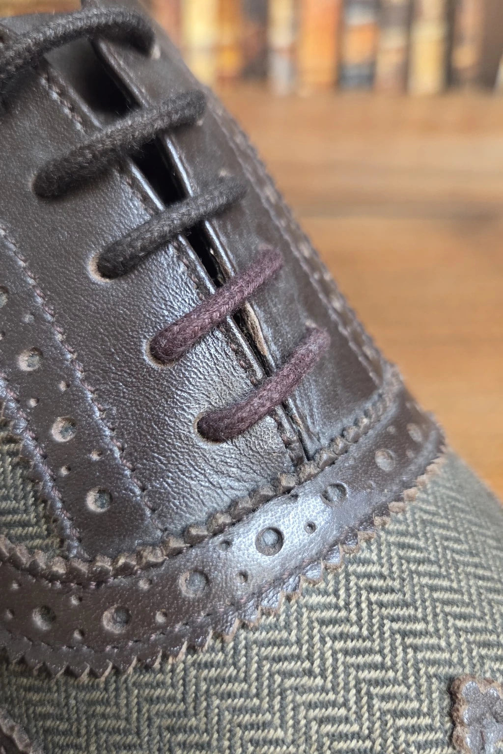 Close-up of a men's Cavani Ellington brown shoe showing the brogue leather lace panel, dark brown laces, and an olive green herringbone fabric toe box.