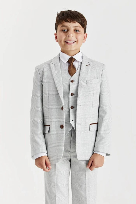 Young boy wearing a Paul Andrew Stone suit with a white shirt and brown tie on a white background