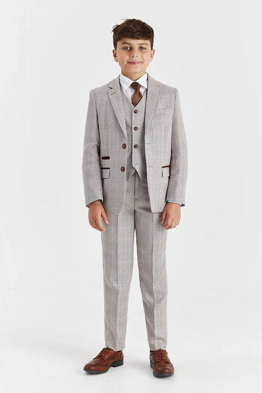 Young boy wearing a beige checkered suit with a white shirt and brown shoes on a white background