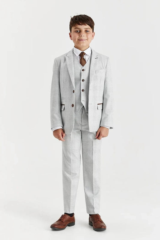 Young boy wearing a Paul Andrew Stone suit with a white shirt and brown tie on a white background