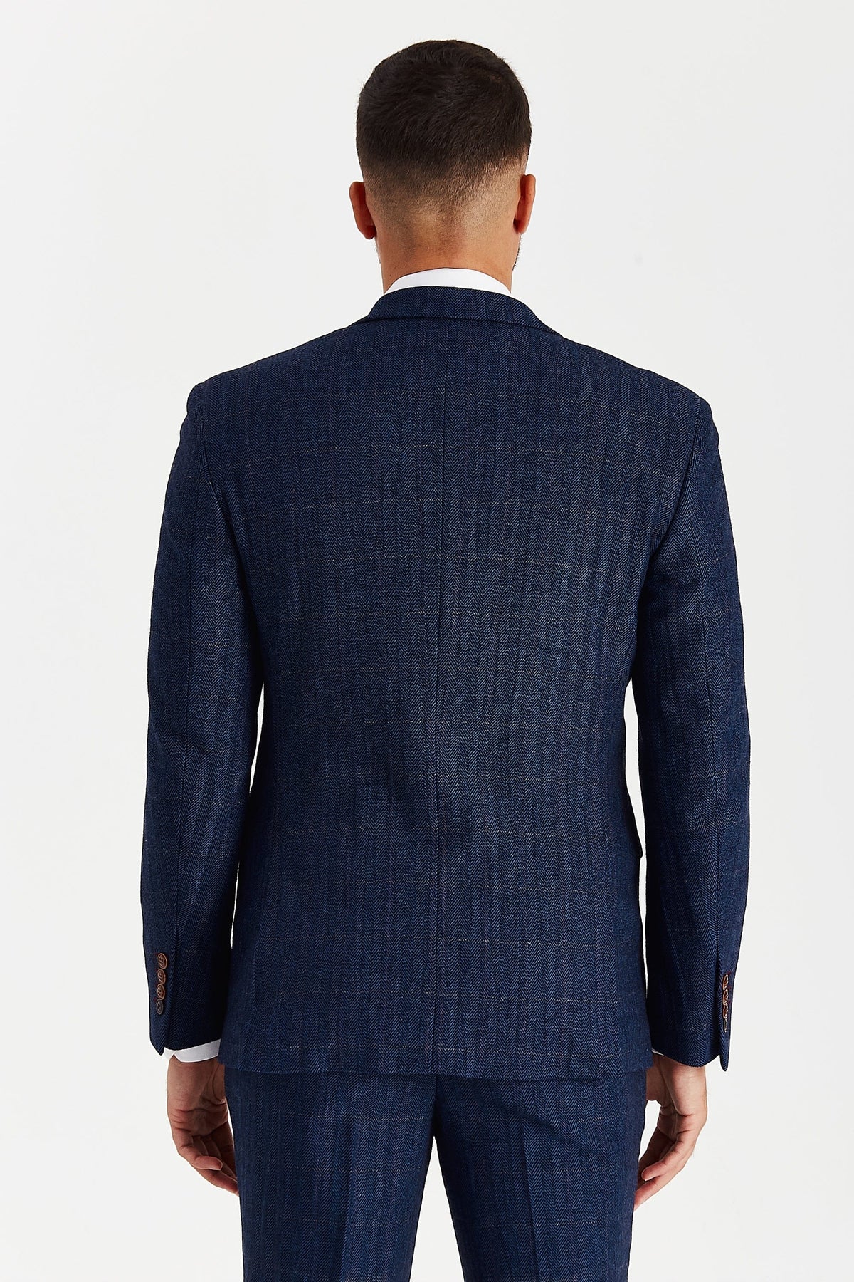 Rear view of a male model wearing the Paul Andrew Scott Navy Tweed Check Three Piece men’s suit from Menz Suits Stockport, highlighting double vents and classic tweed texture.