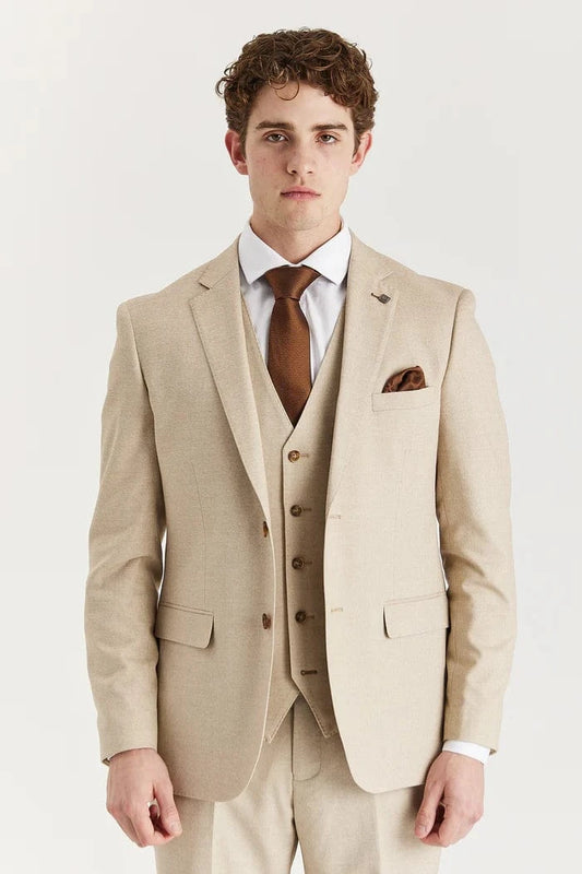 A male model wearing a beige three-piece suit with a jacket, waistcoat, and trousers, paired with a white shirt and brown tie.