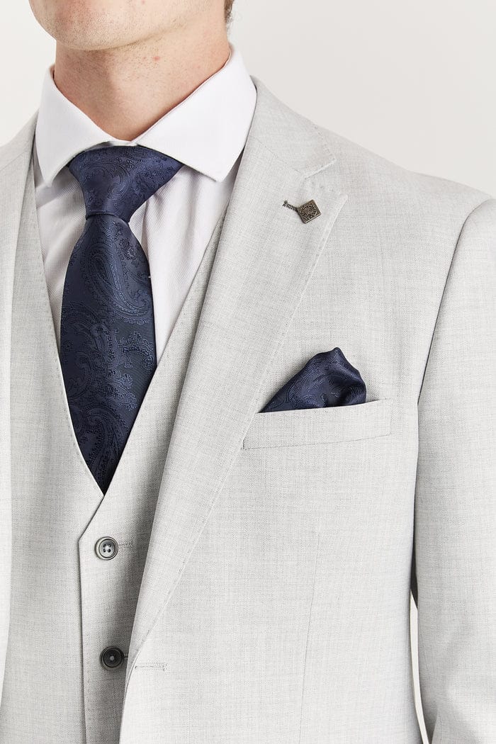 Close-up of the Paul Andrew Belmont Light Grey Three Piece Suit jacket from Menz Suits Stockport, showing navy tie, satin lapel detail, and navy pocket square.