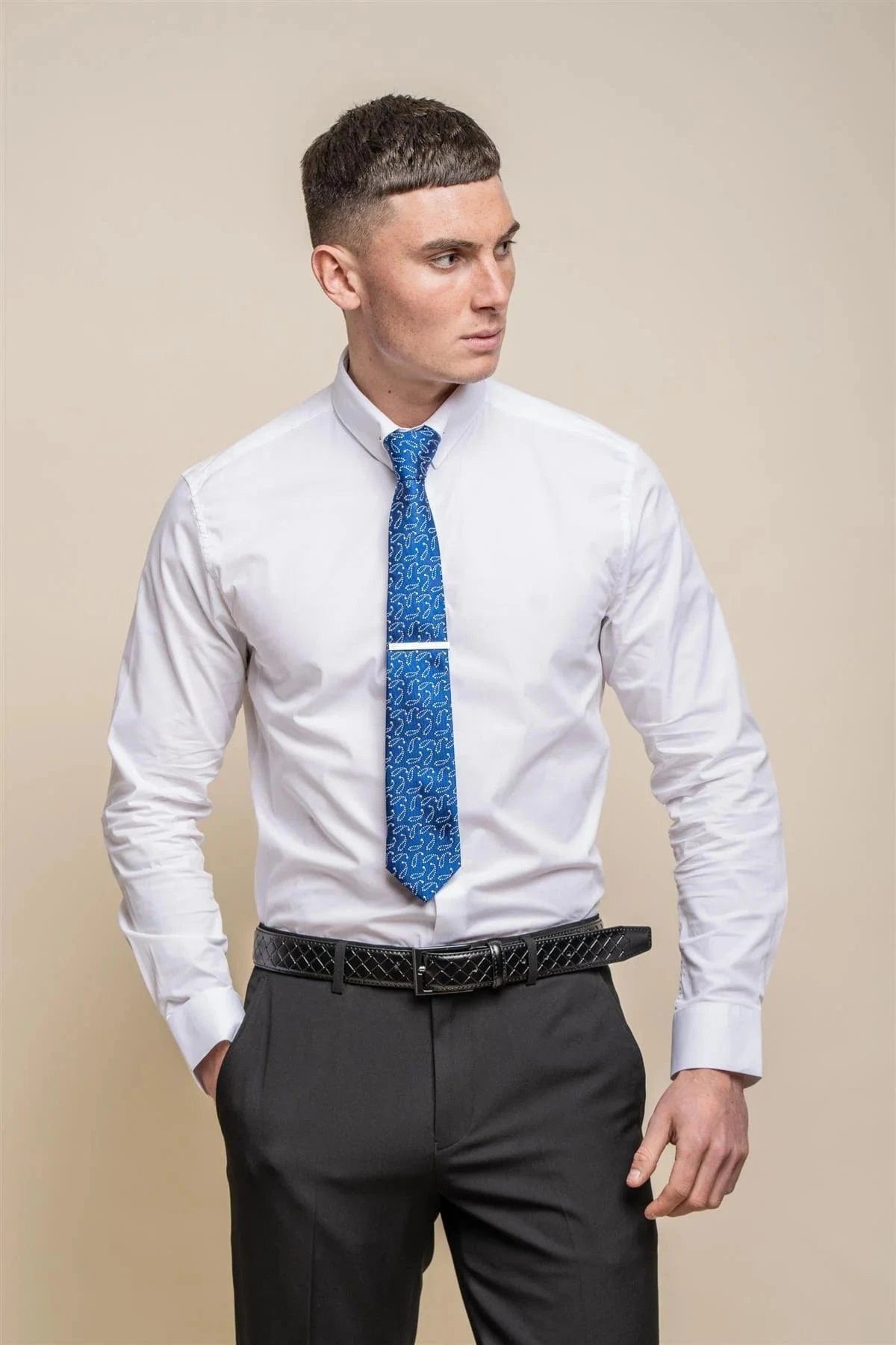 A man wearing a white long sleeve slim fit dress shirt with a pin collar, paired with a blue tie and black trousers.