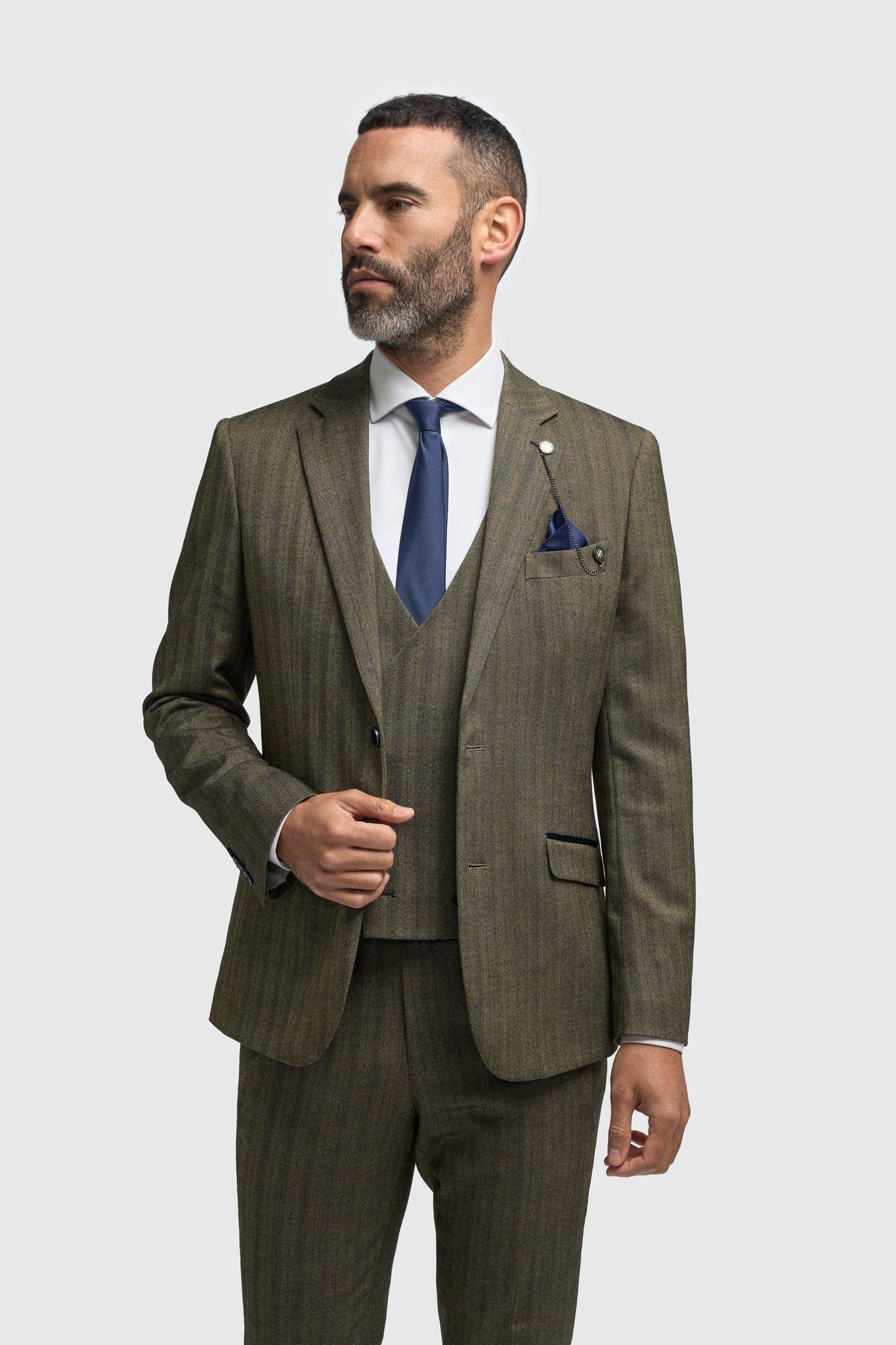 Man wearing a Cavani Damon Sage Tweed suit with a white shirt and blue tie on a white background