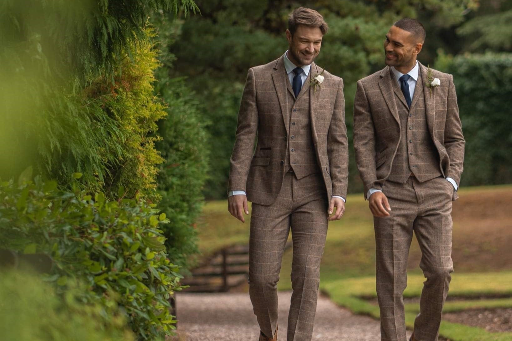 Two men walking smiling, wearing Cavani Albert brown tweed 3 piece suits while attending a wedding.