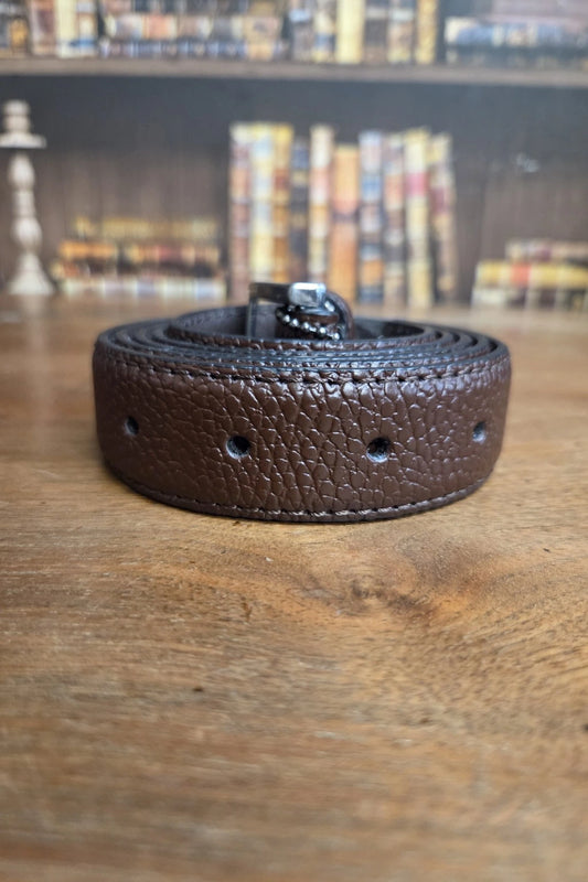 A dark brown textured leather belt with a silver buckle, coiled on a wooden tabletop with a blurred bookshelf background.