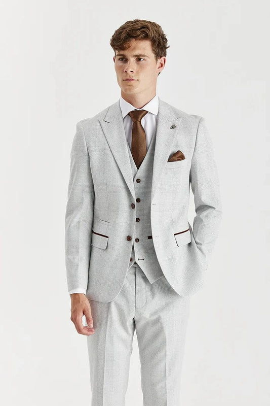 Man wearing a Paul Andrew stone check suit with a white shirt and brown shoes on a white background