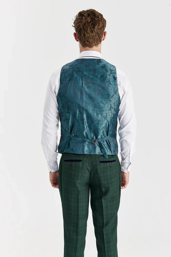 Man wearing a teal patterned vest over a white shirt and green plaid pants on a white background