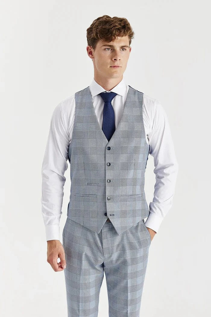 Man wearing a sky blue checkered suit vest over a white shirt with a blue tie on a light gray background