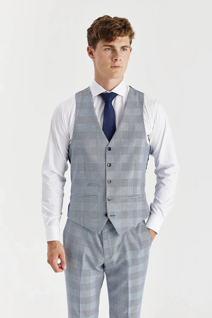 Man wearing a sky blue checkered suit vest over a white shirt with a blue tie on a light gray background