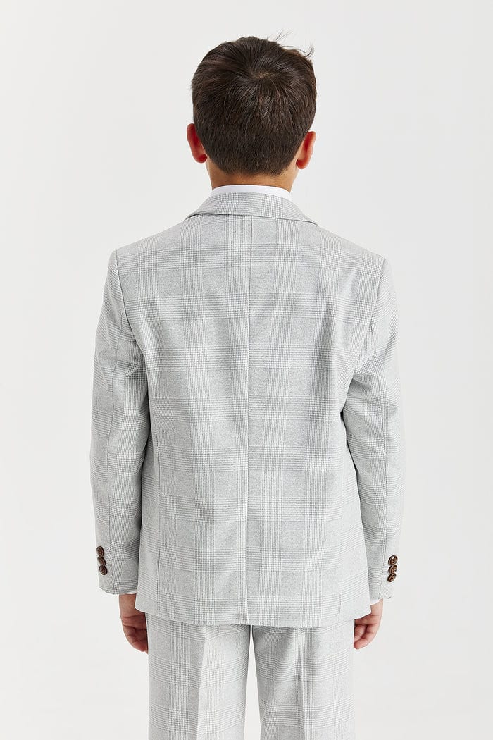 Young boy wearing a Paul Andrew Stone suit with a white shirt and brown tie on a white background