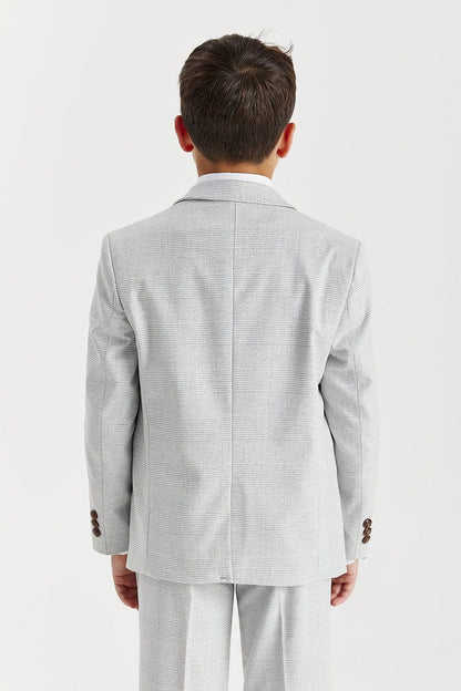 Young boy wearing a Paul Andrew Stone suit with a white shirt and brown tie on a white background