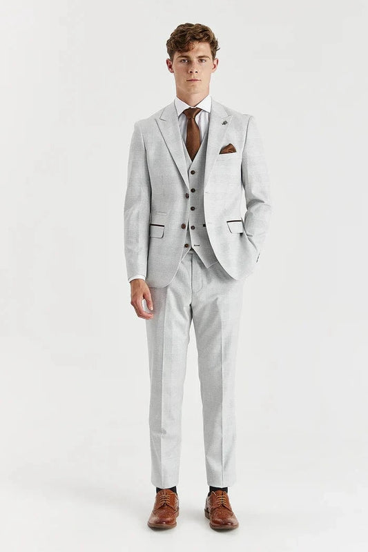 Man wearing a Paul Andrew stone check suit with a white shirt and brown shoes on a white background