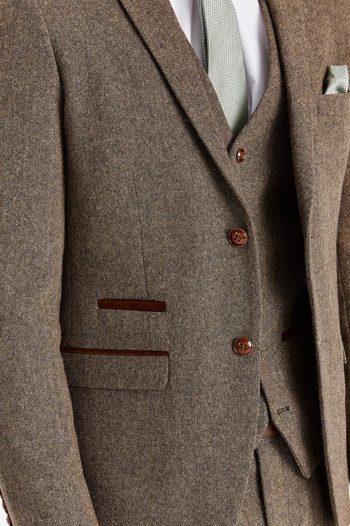 Close-up of a brown tweed suit with buttons and pocket details.