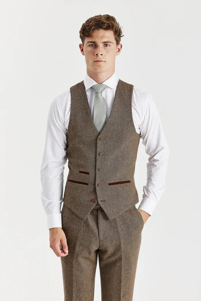 Man wearing a brown tweed suit vest with a white shirt and light gray tie on a white background