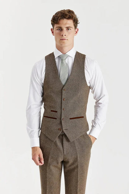 Man wearing a brown tweed suit vest with a white shirt and light gray tie on a white background
