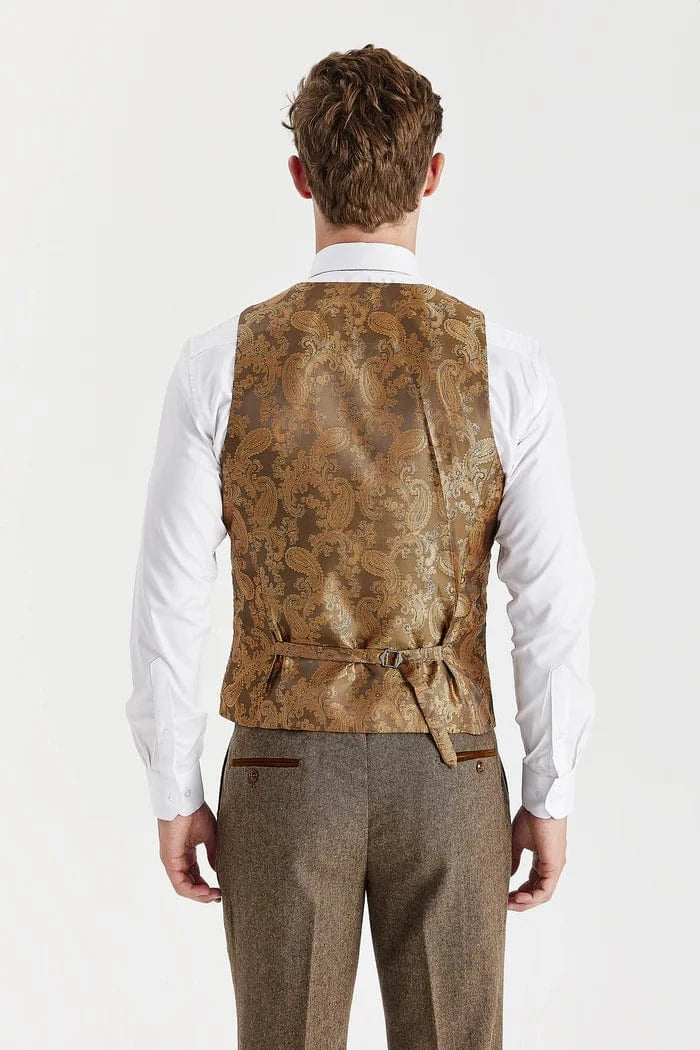 Man wearing a brown patterned vest over a white shirt and gray pants on a white background