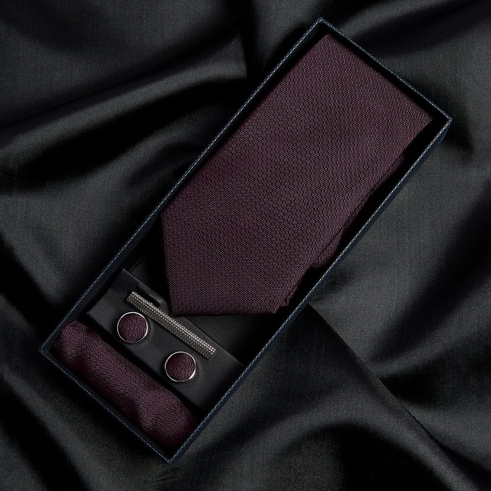 Paul Andrew burgundy tie, pocket square, and cufflinks set on black fabric