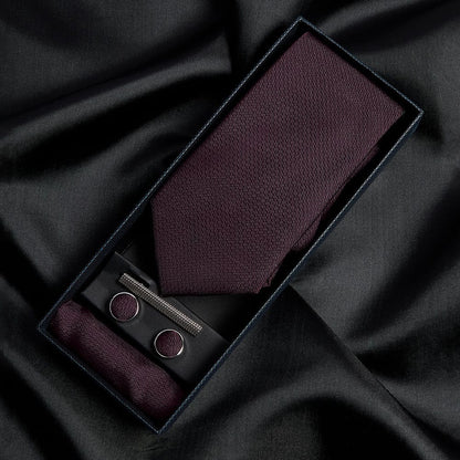 Paul Andrew burgundy tie, pocket square, and cufflinks set on black fabric