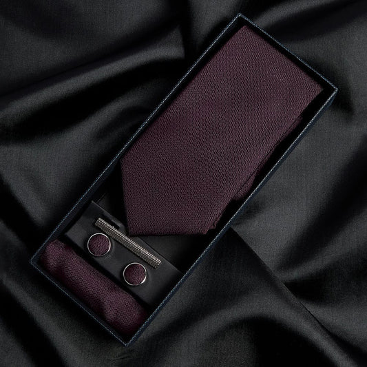 Paul Andrew burgundy tie, pocket square, and cufflinks set on black fabric