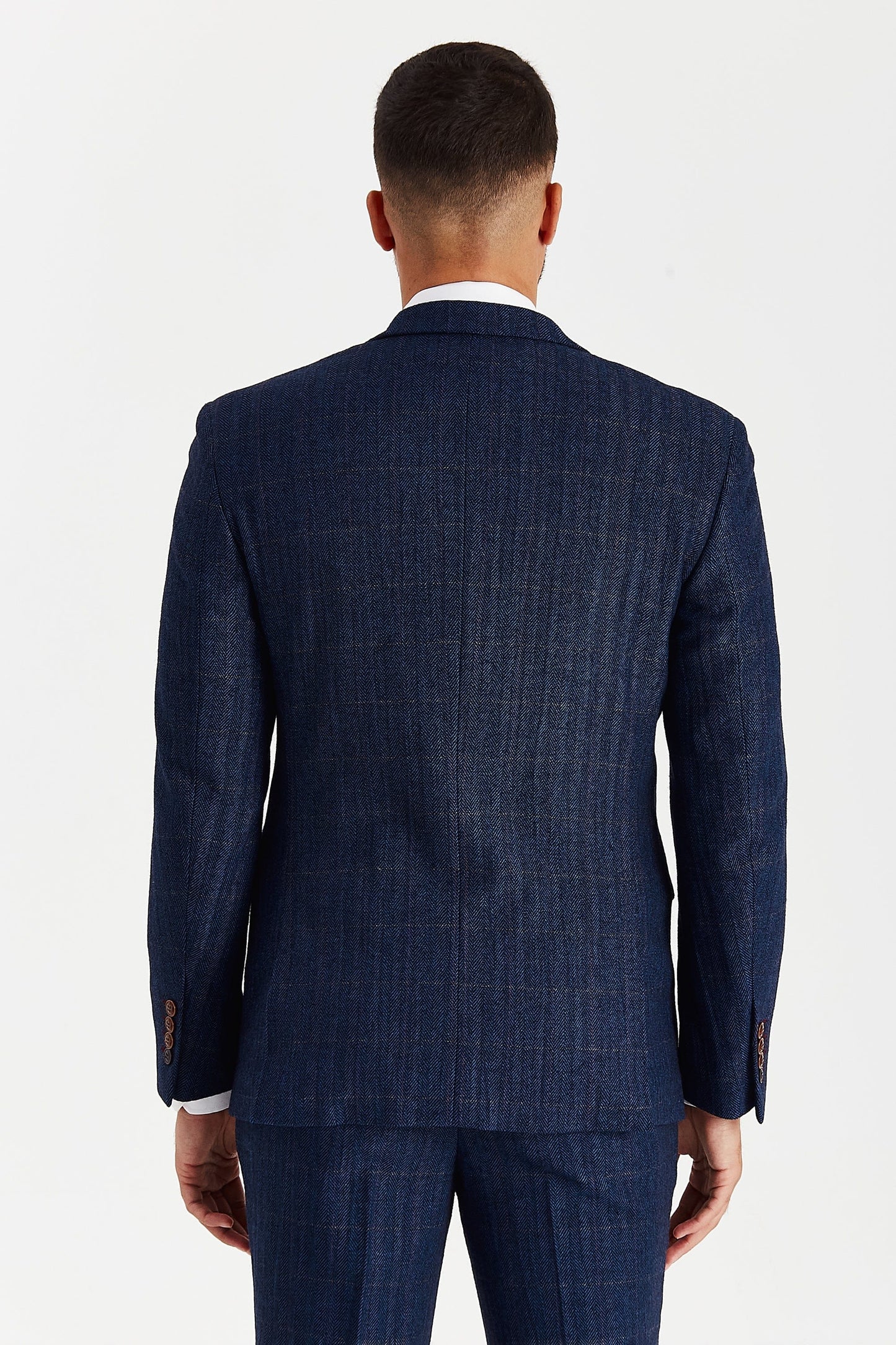 Rear view of a male model wearing the Paul Andrew Scott Navy Tweed Check Three Piece men’s suit from Menz Suits Stockport, highlighting double vents and classic tweed texture.