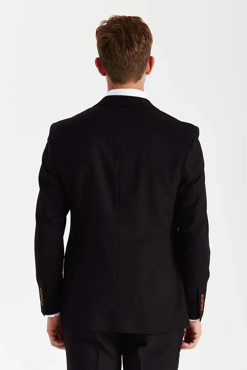 Rear view of a male model wearing the Paul Andrew Mayfair Black Three Piece men’s suit from Menz Suits Stockport, highlighting the back vents and black fabric.