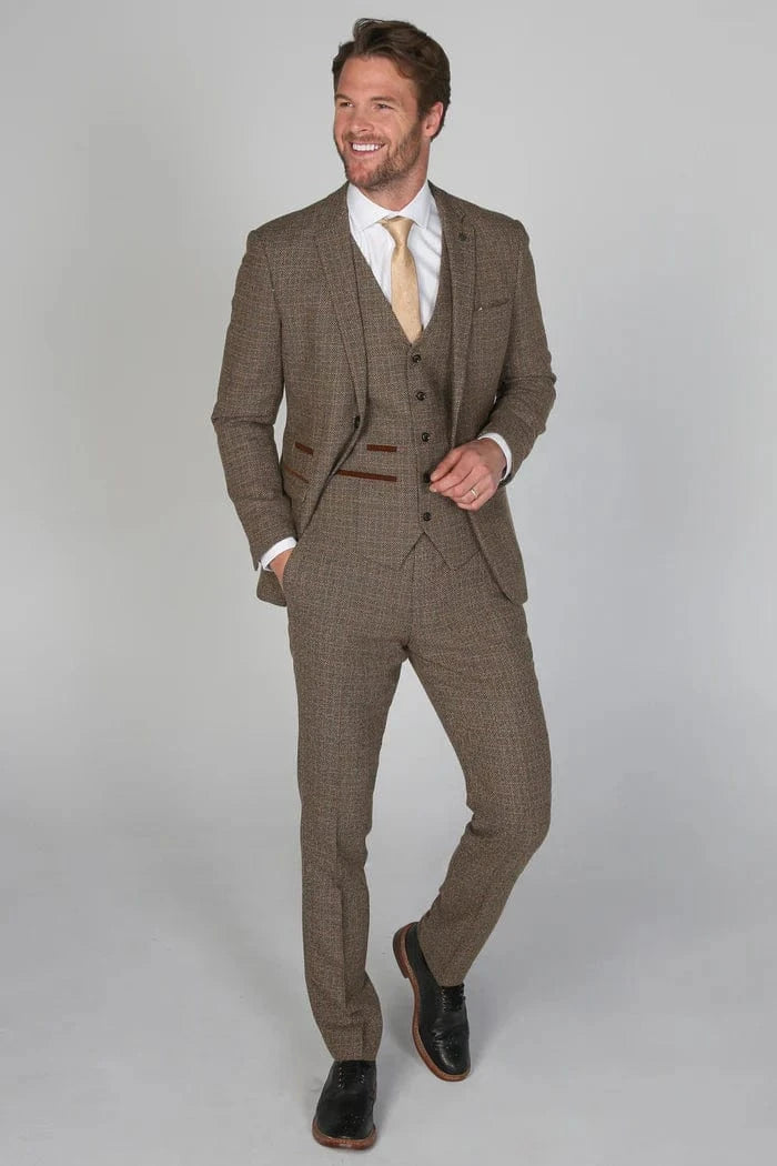 Man wearing a brown checkered suit with a white shirt and yellow tie on a gray background