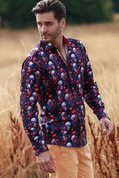 Man wearing a Claudio Lugli patterned shirt with skulls and flowers and peach pants standing in a field.