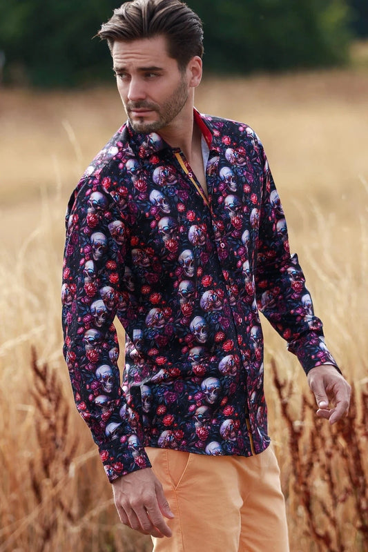 Man wearing a Claudio Lugli patterned shirt with skulls and flowers and peach pants standing in a field.