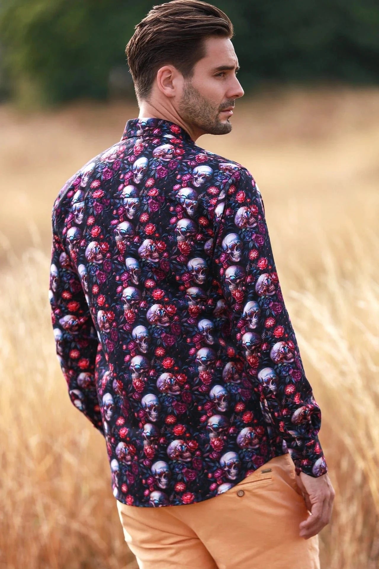 Man wearing a Claudio Lugli floral and skull patterned shirt with in a field.