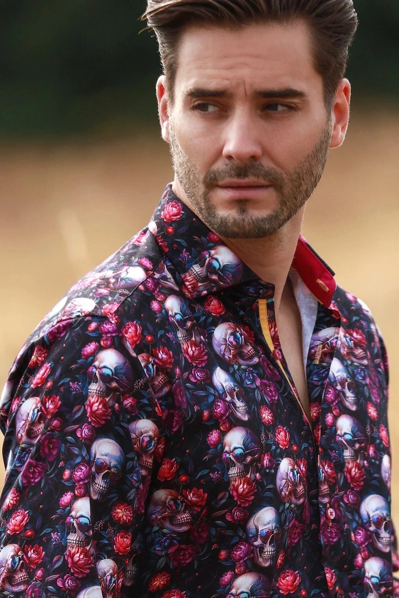 Man wearing a Claudio Lugli floral and skull patterned shirt with a blurred background.