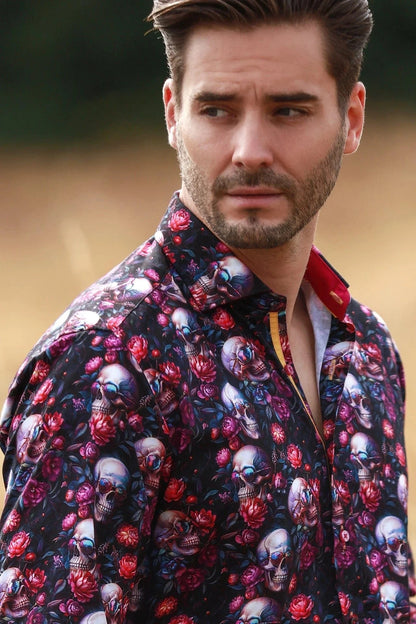 Man wearing a Claudio Lugli floral and skull patterned shirt with a blurred background.