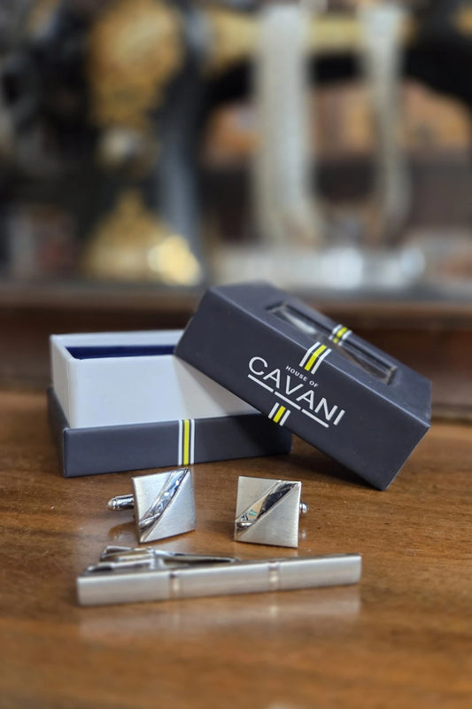 A men's formal accessory set including a silver tie clip, matching square cufflinks, and an open presentation box with the lid leaning on top. The box is dark navy blue with yellow and white stripes and the brand name 'CAVANI' printed on the lid.