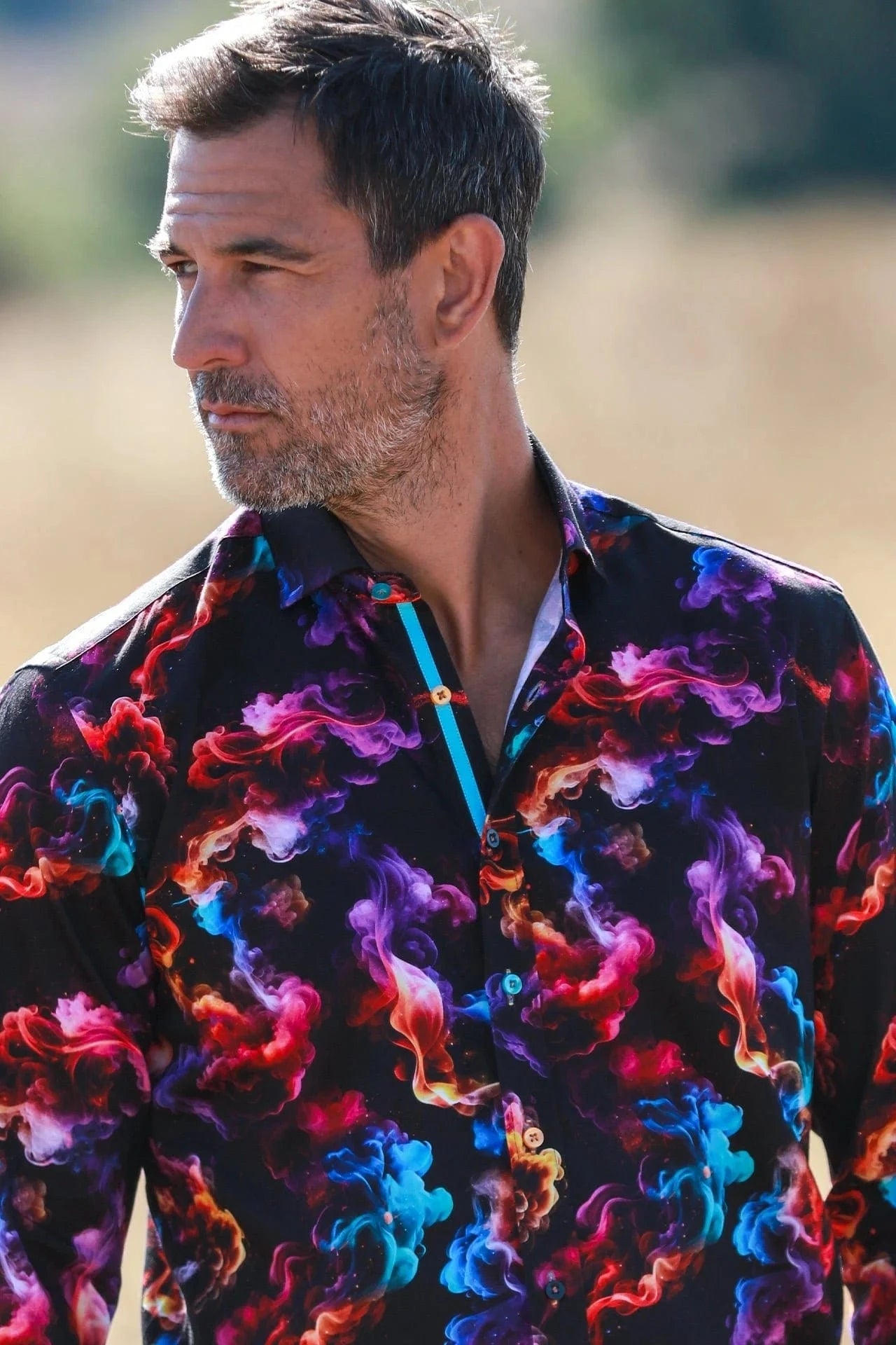 Man wearing a colorful Claudio Lugli shirt with a blurred outdoor background
