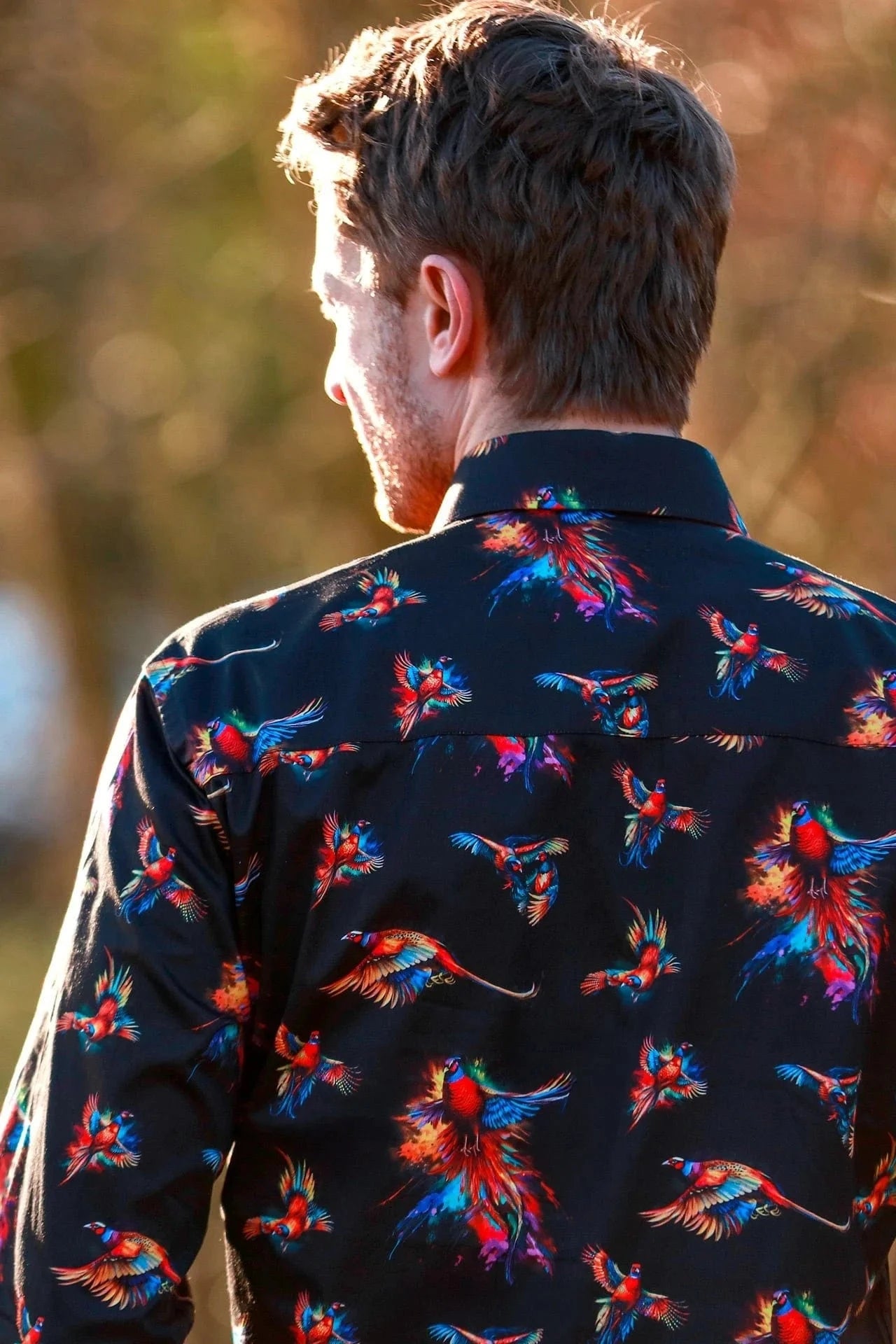 Man wearing a dark Claudio Lugli  shirt with watercolour pheasant pattern outdoors